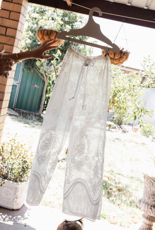 White pants hanging on a clothesline with a blurred outdoor background